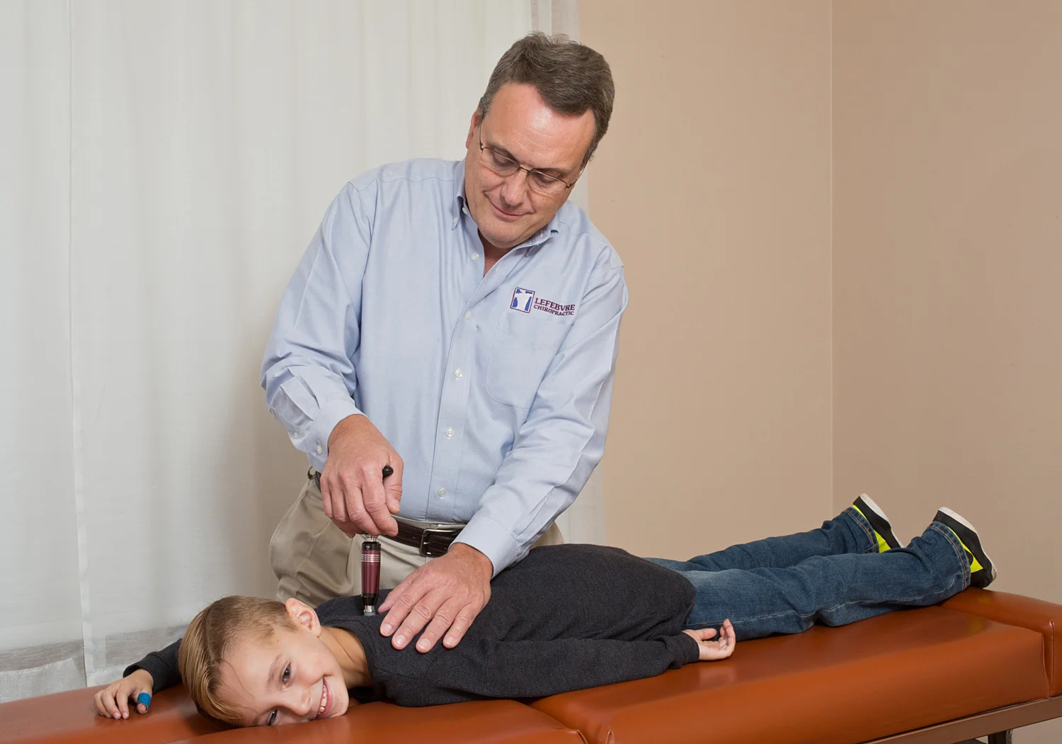 Dr. Lefebvre using an Activator instrument during a chiropractic visit